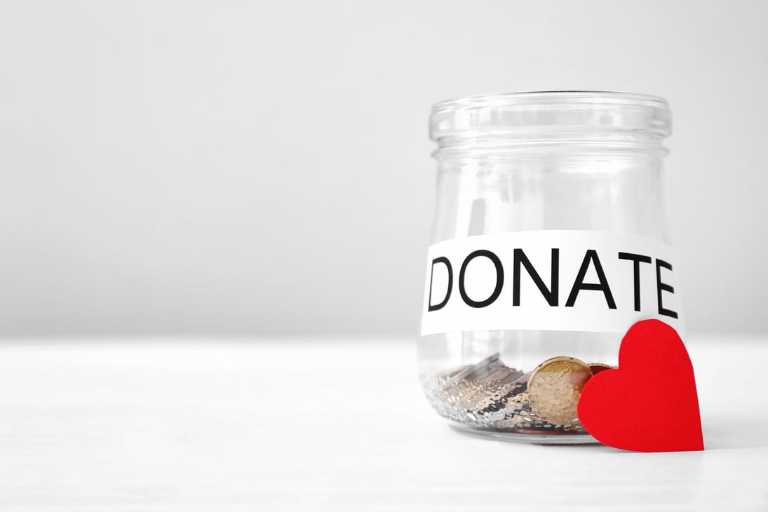 Glass Jar with Coins and Red Heart on Table. Concept of Donations